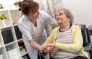 Nurse supporting elderly woman in nursing home