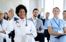 Group of healthcare workers and business people attending an educational event in board room. Focus is on happy African American doctor with raised ands.